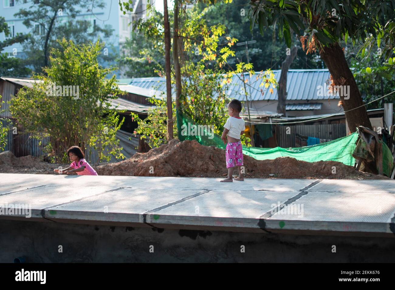 YANGON, MYANMAR - DEZEMBER 31 2019: Zwei junge burmesische Kinder spielen zusammen an einem Bahnhof außerhalb von Yangon Stockfoto