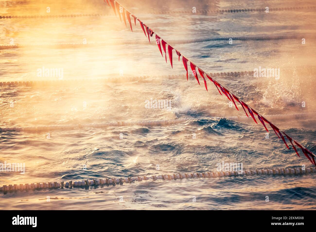 Flurspuren und Flaggen im Schwimmbad mit Nebel über dem Wasser. Sportwettbewerb. Stockfoto