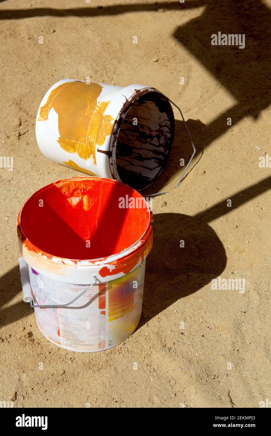 Ein paar leere Farbeimer mit roten und befleckt Schwarze Farben auf dem sandigen Boden hinterlassen Stockfoto