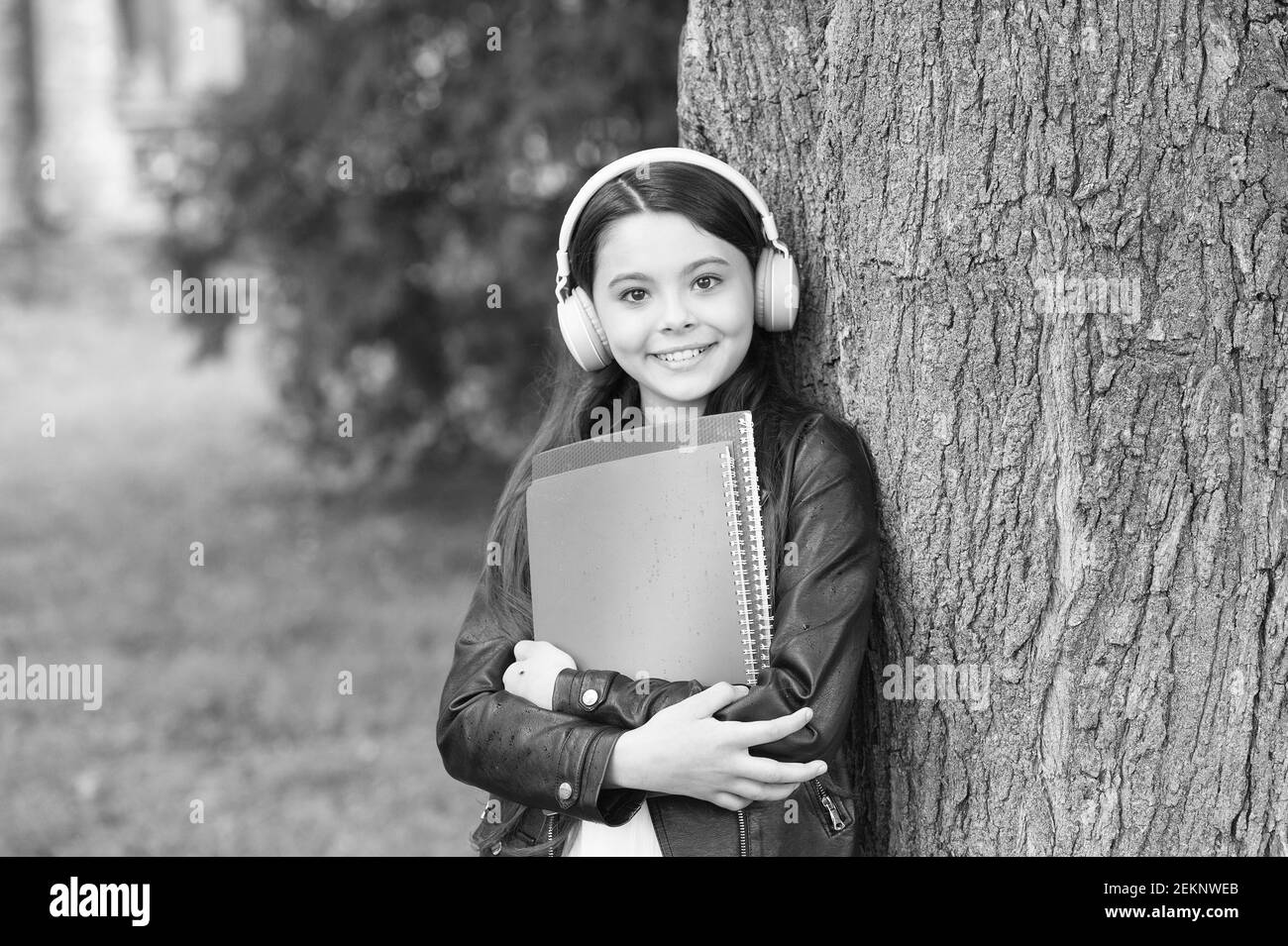 Mädchen hören Audio tragen Lehrbücher entspannend Park Hintergrund, Sound in ihrem Kopf Konzept. Stockfoto