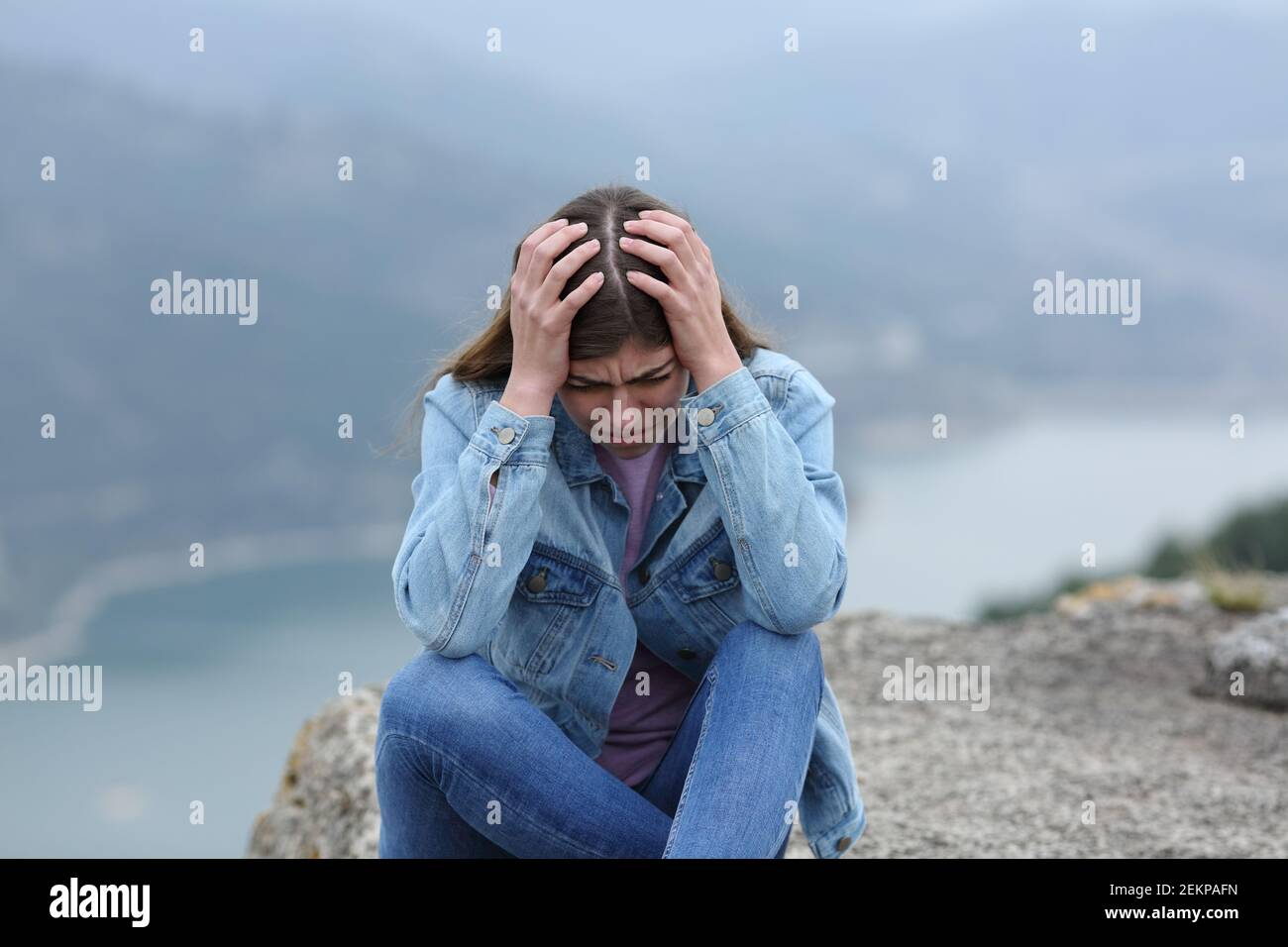 Traurige alleinstehende Teenager-Frau, die sich in einer Klippe in der beschwert Berg Stockfoto