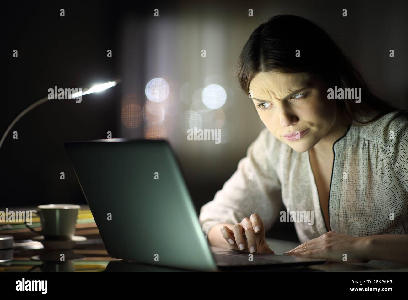 Verdächtige Unternehmerin Frau Überprüfung Laptop-Inhalte spät in den Stunden Nacht zu Hause Stockfoto
