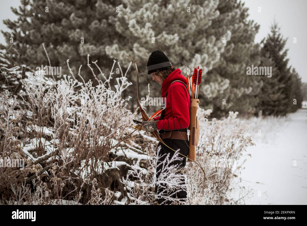 Teen junge Blick auf Tierfalle im Winter Wisconsin mit Pfeil und Bogen Stockfoto