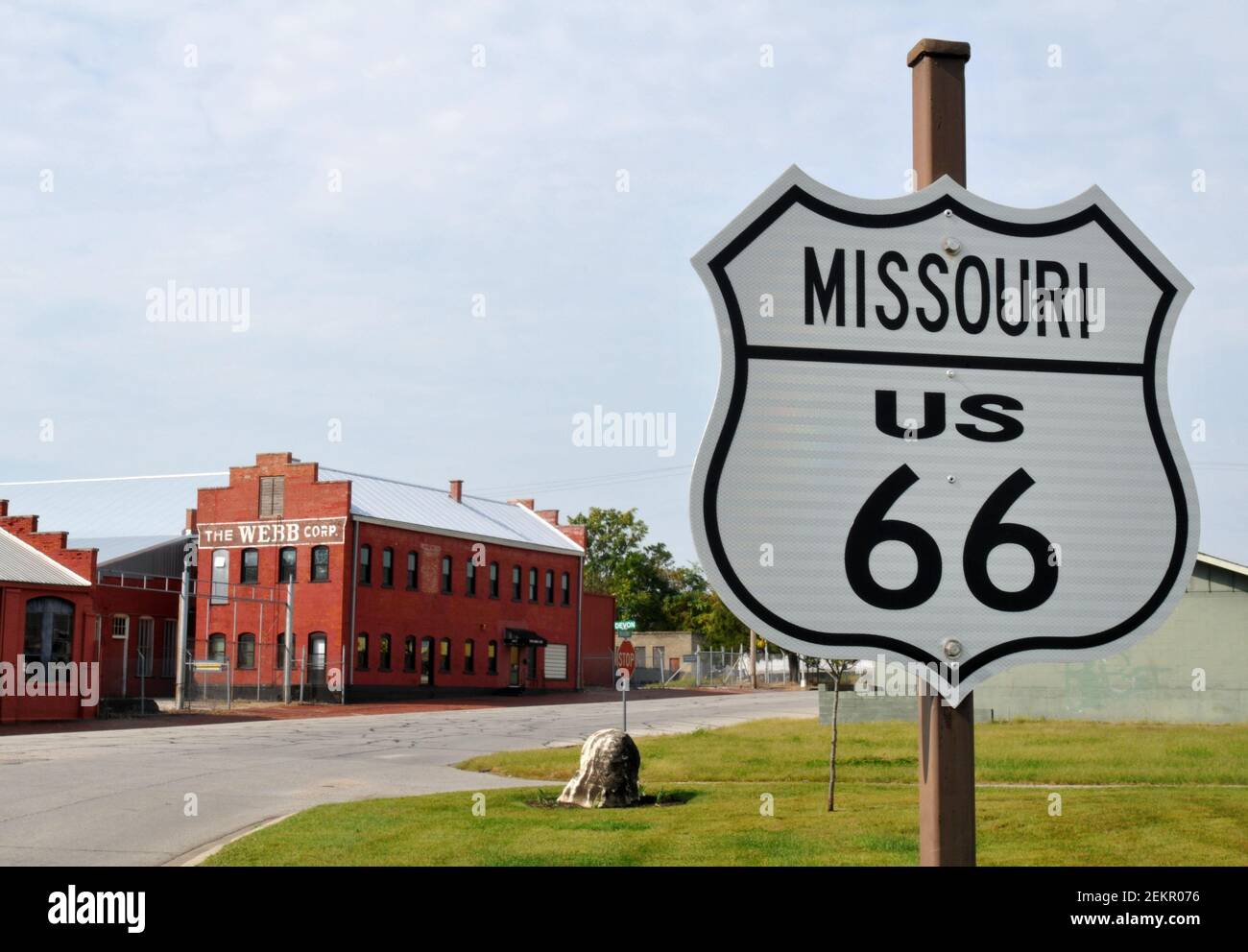 Ein US 66 Straßenschild markiert Route 66 durch Webb City, Missouri. Der INDUSTRIEKOMPLEX DER WEBB Corporation (Hintergrund) steht seit 1881 auf dem Gelände. Stockfoto