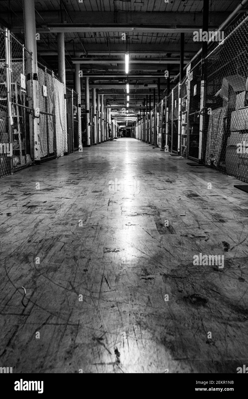 Eine grungige Halle in einer Fabrik, die zu Lagereinheiten umgebaut wurde, schafft führende Linien und Perspektiven. Stockfoto