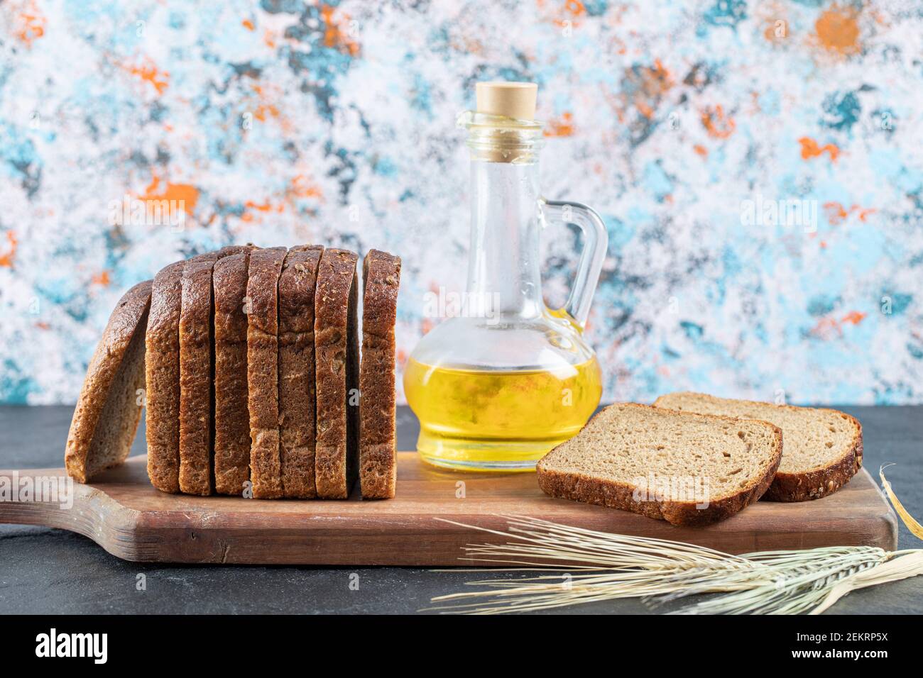 Braune Brotscheiben und Ölflasche auf Holzbrett Stockfoto