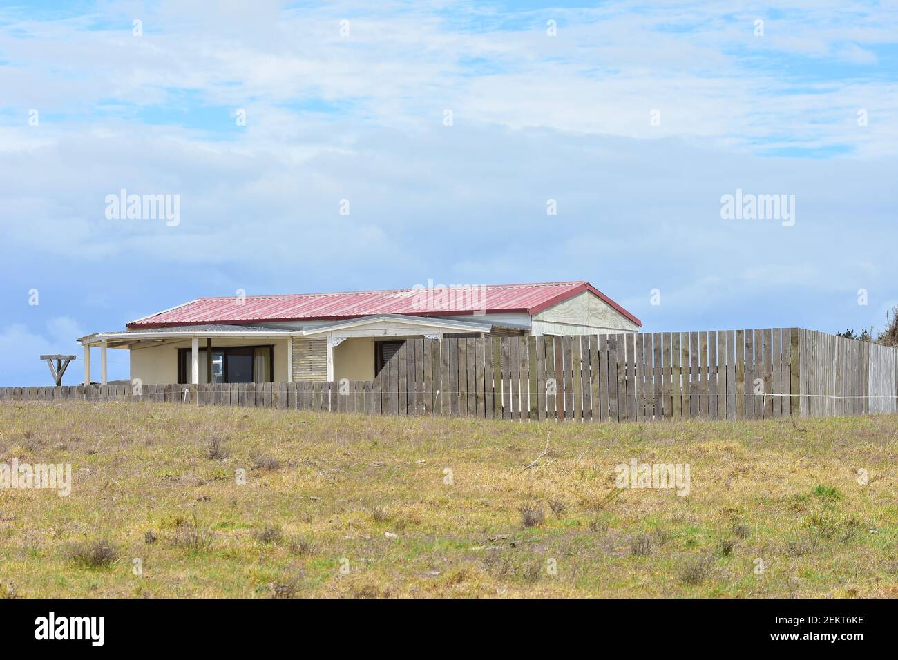 Ländliches Holzhaus mit Blechdach und Schieferzaun in trockenem Paddock platziert. Stockfoto