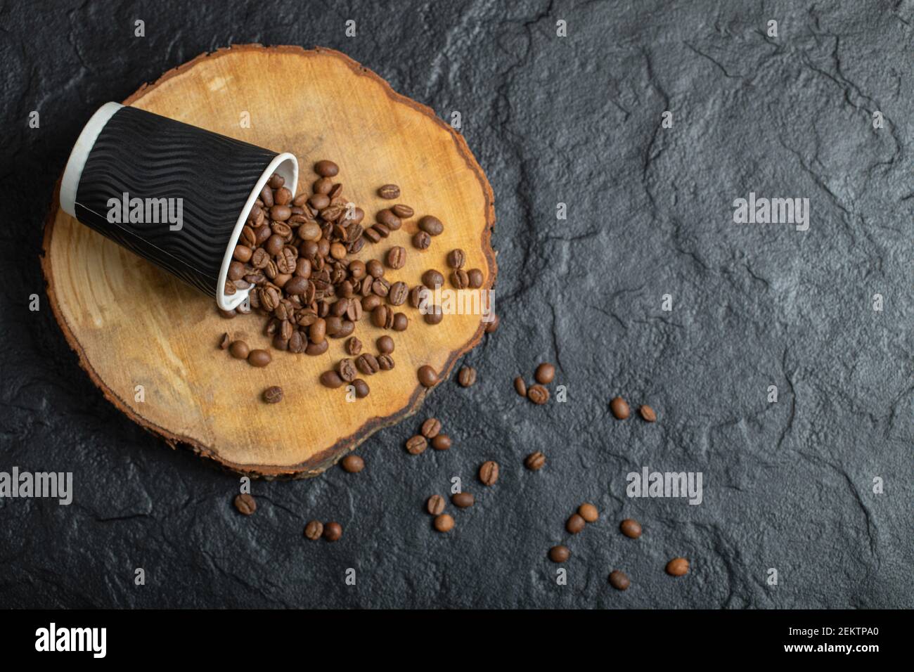 Eine schwarze Tasse voller Kaffeebohnen auf einem Holzkäfige Platine Stockfoto