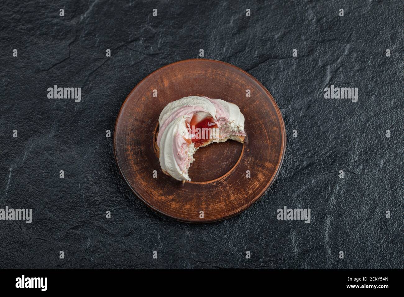Ein köstlicher Cupcake auf einem braunen Teller gebissen Stockfoto