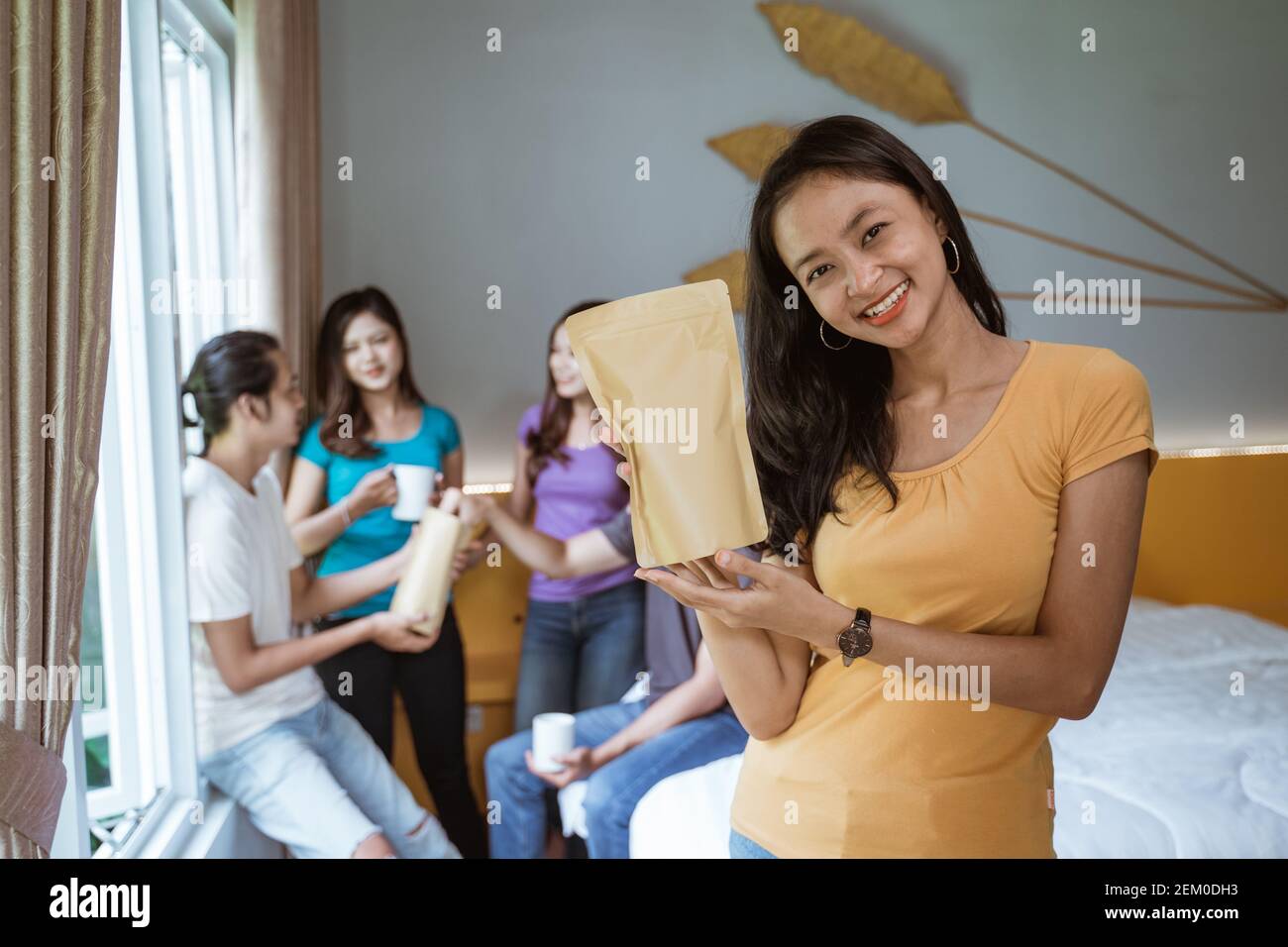 Fünf asiatische junge Freund mit Spaß zusammen im Schlafzimmer. Produkt mockup halten von Frau Stockfoto