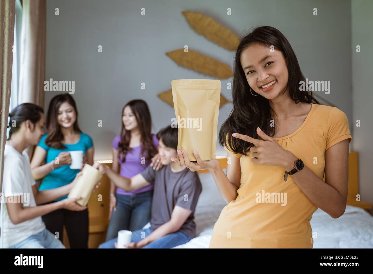 Fünf asiatische junge Freund mit Spaß zusammen im Schlafzimmer. Produkt mockup halten von Frau Stockfoto