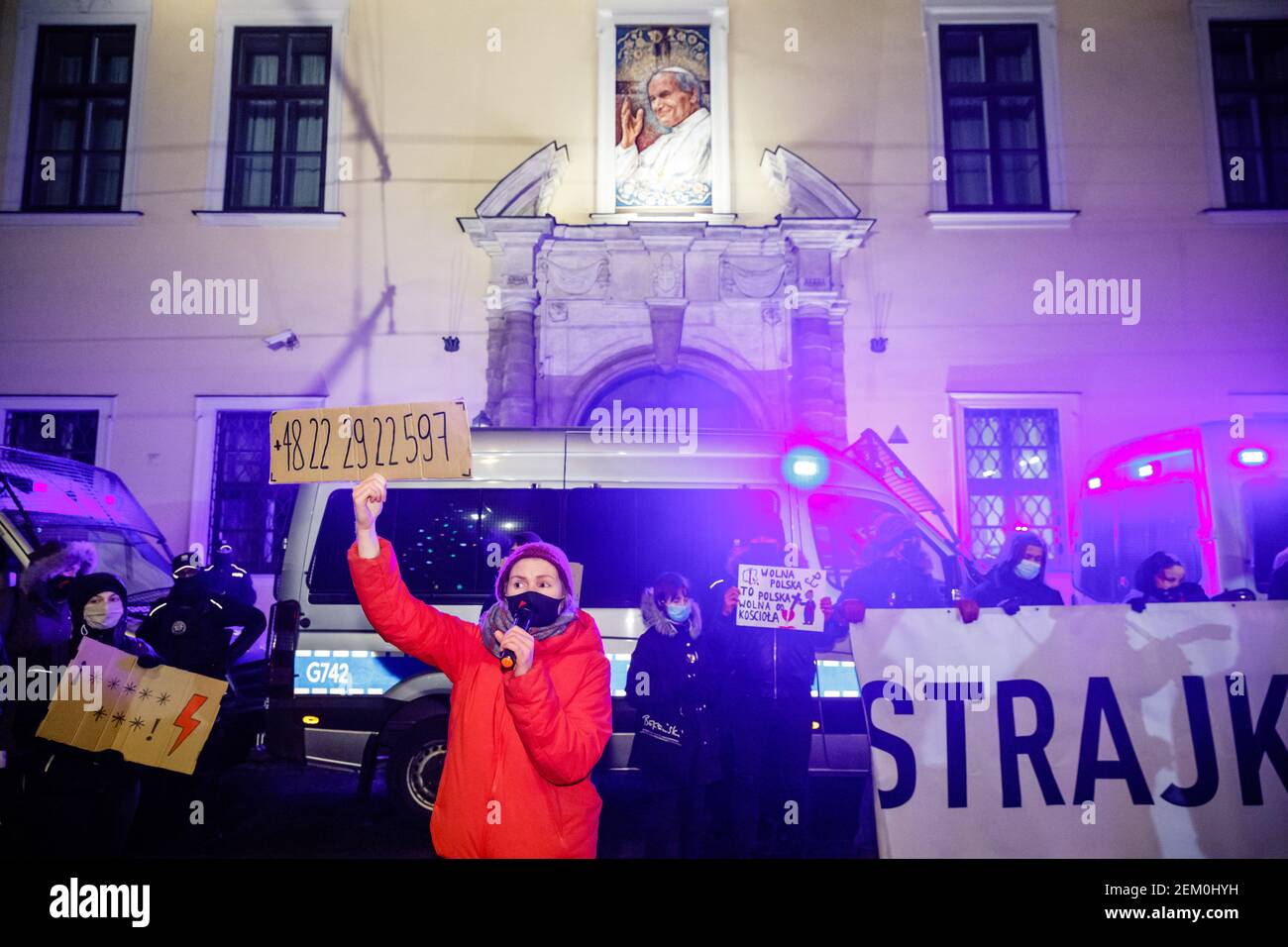 Ein Protestler trägt eine Maske und hält ein Plakat mit Eine Telefonnummer für eine professionelle Organisation ist in zu sehen Vorderseite der katholischen Metropolregion Curia BU Stockfoto