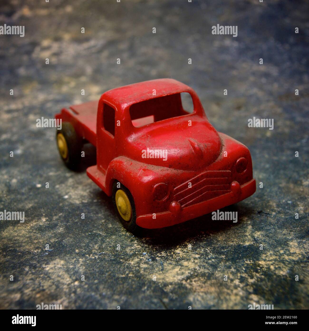 Ein roter Vintage-Truck auf einer strukturierten Oberfläche mit rustikalem Aussehen, perfekt für nostalgische Spielmomente Stockfoto