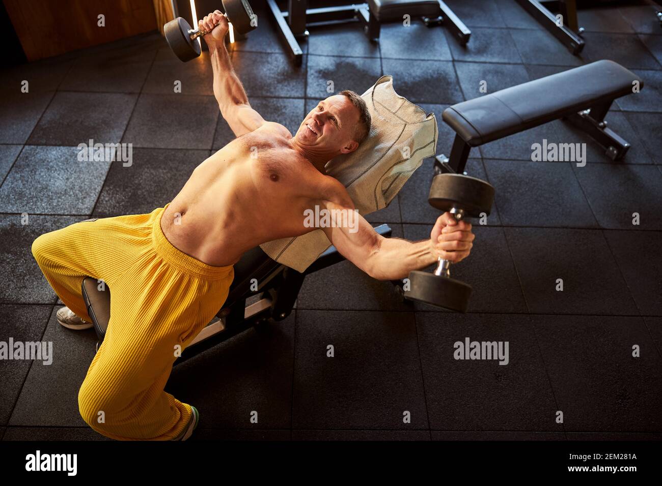 Optimistischer Sportler, der beim Hanteln-Workout voller Energie aussieht Stockfoto