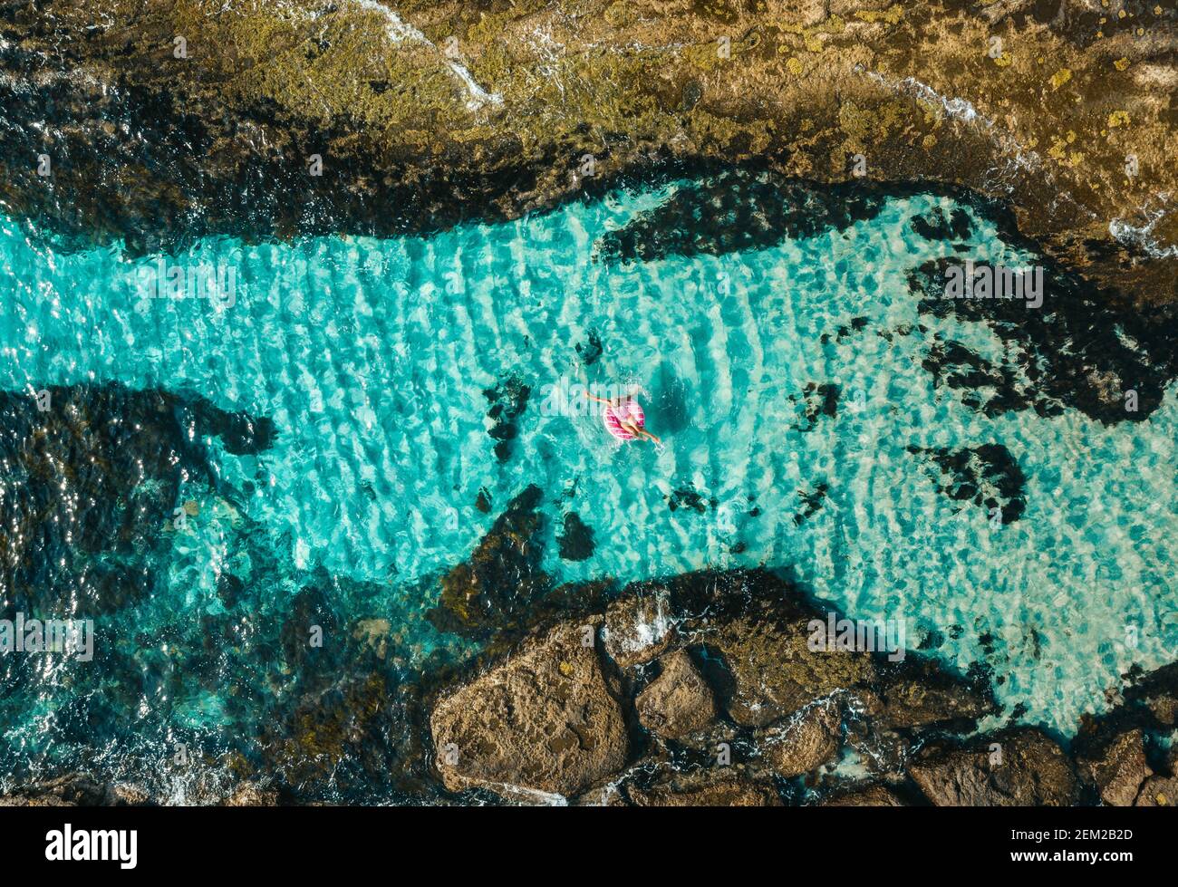 Weibchen schwimmend in einem Donut Schwimmring Spielzeug in der meer mit idyllischem kristallblauem Wasser Stockfoto