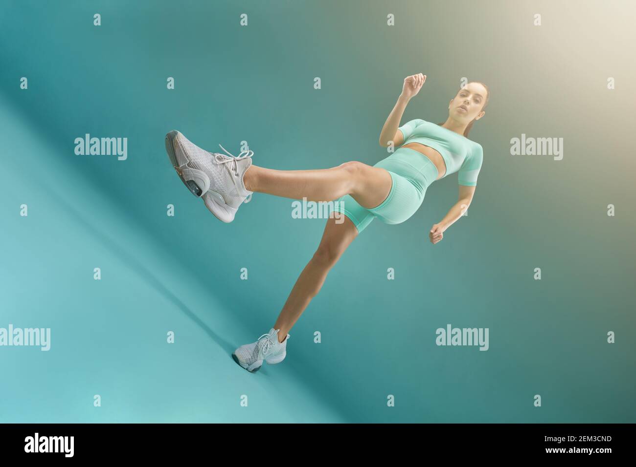 Charming fit Dame trägt Sport Crop Top und Shorts während der Ausübung. Isoliert auf blauem Hintergrund Stockfoto