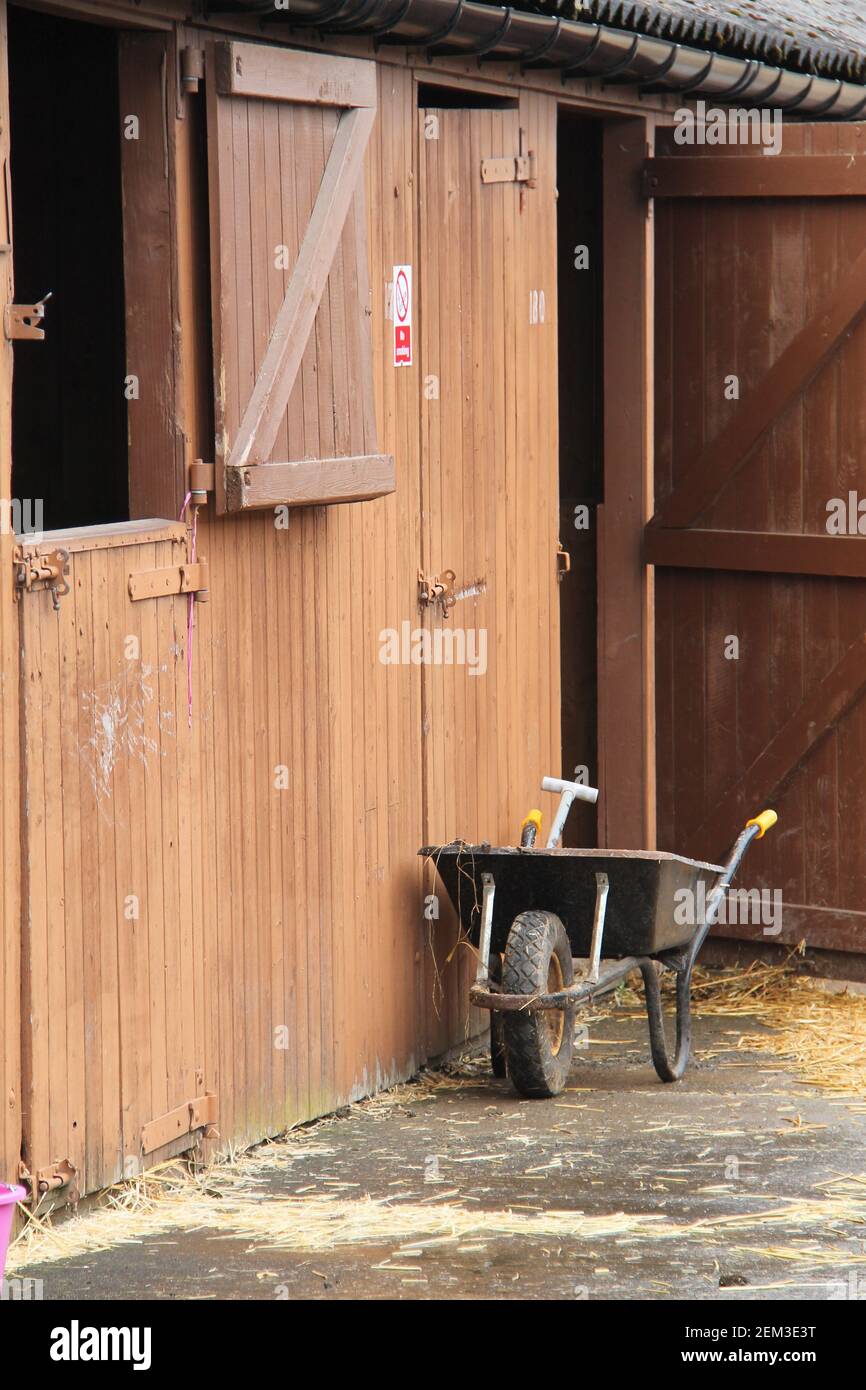 Ein ausmuckender Schubkarre an einem Pferdestall. Stockfoto