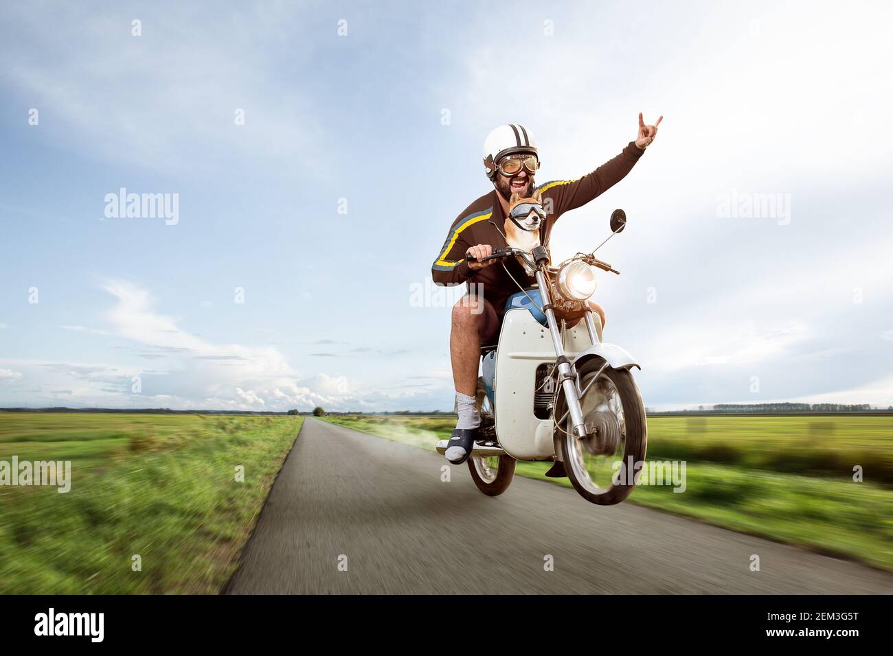 Lustiger Biker, der mit seinem Moped ein Wheelie macht Stockfoto