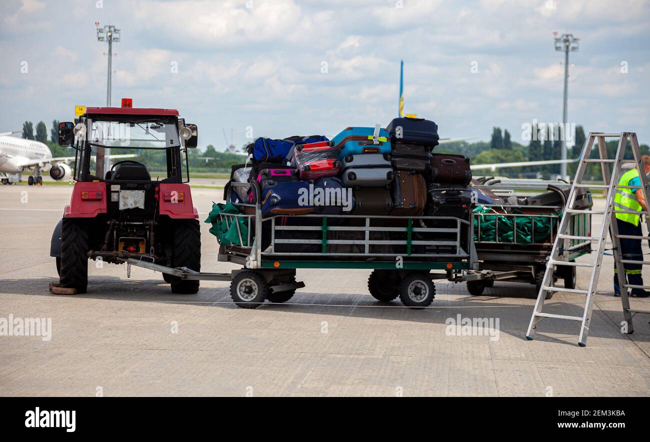 Trolley mit Gepäck am Flughafen auf dem Bahnsteig in der Nähe des Flugzeugs. Reisekoffer. Koffer für Passagiere. Sonderausrüstung Minitraktor. Stockfoto