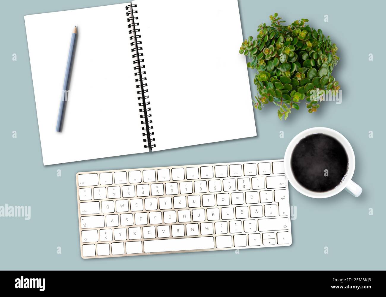 Draufsicht Schreibtischvorlage mit Computertastatur, Spiralnotizblock mit Kopierraum, Bleistift, Kaffeetasse und Topfpflanze Stockfoto