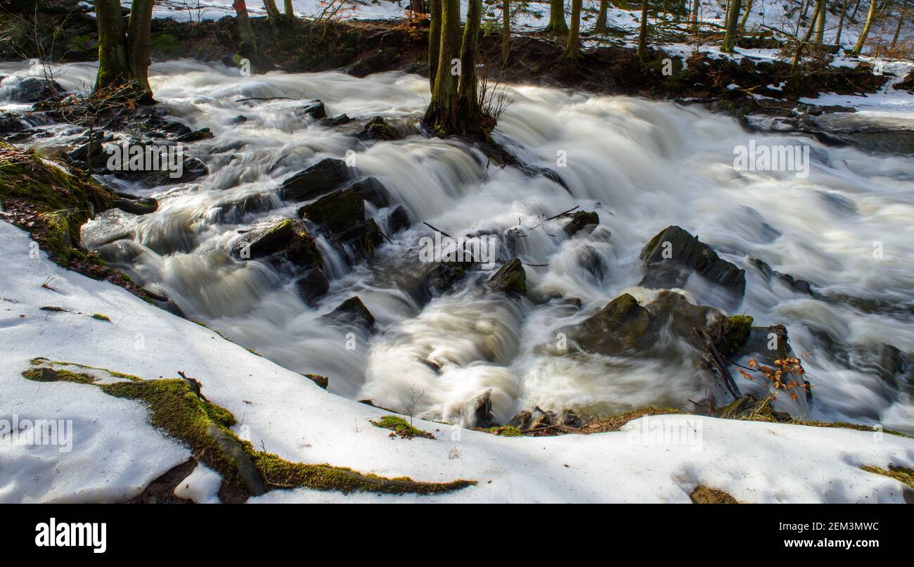 Alexisbad, Deutschland. Februar 2021, 24th. Wasser fließt über die Kaskaden der Selke Falls. Auch im Harz ist ein Tauwetter einge-setzt. Nur in den Wäldern haben Schneefelder die frühlingshaften Temperaturen überlebt. Es soll die ganze Woche sonnig bleiben, aber gegen Ende der Woche wird es wieder kälter. Quelle: Klaus-Dietmar Gabbert/dpa-Zentralbild/dpa/Alamy Live News Stockfoto