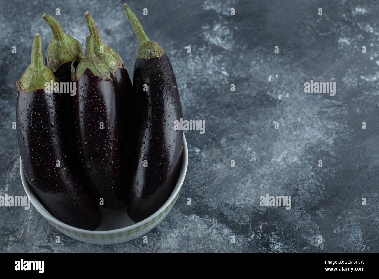 Stapel von Bio-rohen Auberginen in Schale auf grauem Hintergrund Stockfoto