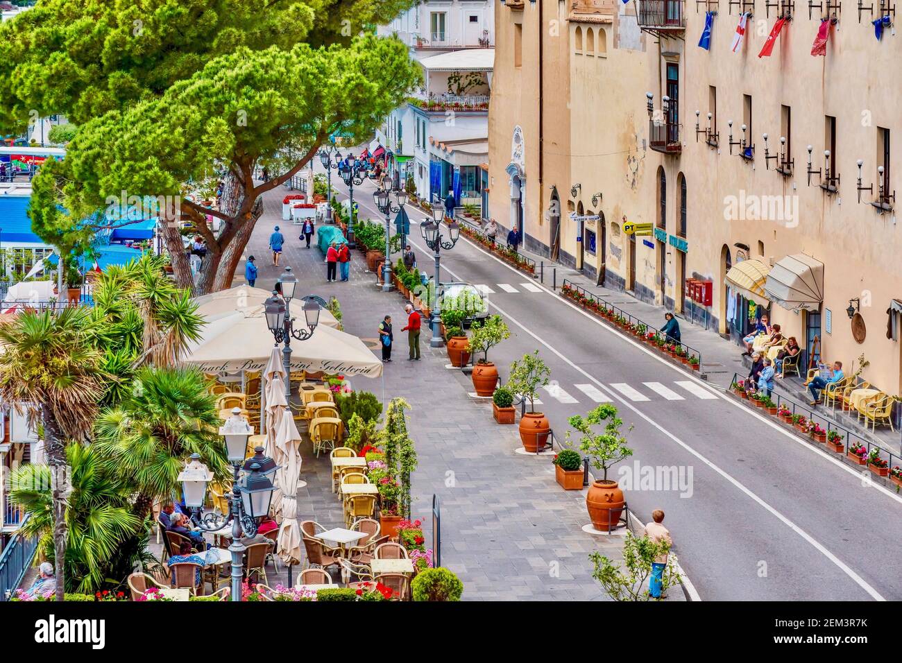 Amalfi, Italien - 20. Mai 2016. Eine Hauptstraße mit Cafés, Geschäften und Bäumen in der Stadt, die der Amalfiküste ihren Namen gibt gesäumt. Stockfoto