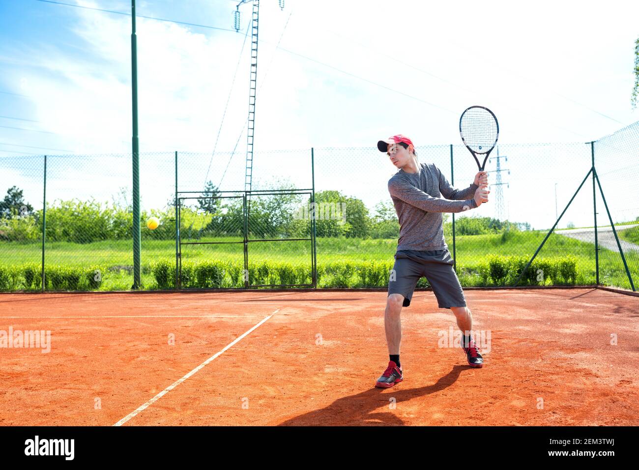 Junger Mann, der auf dem Sandplatz trainiert und Tennis spielt Stockfoto