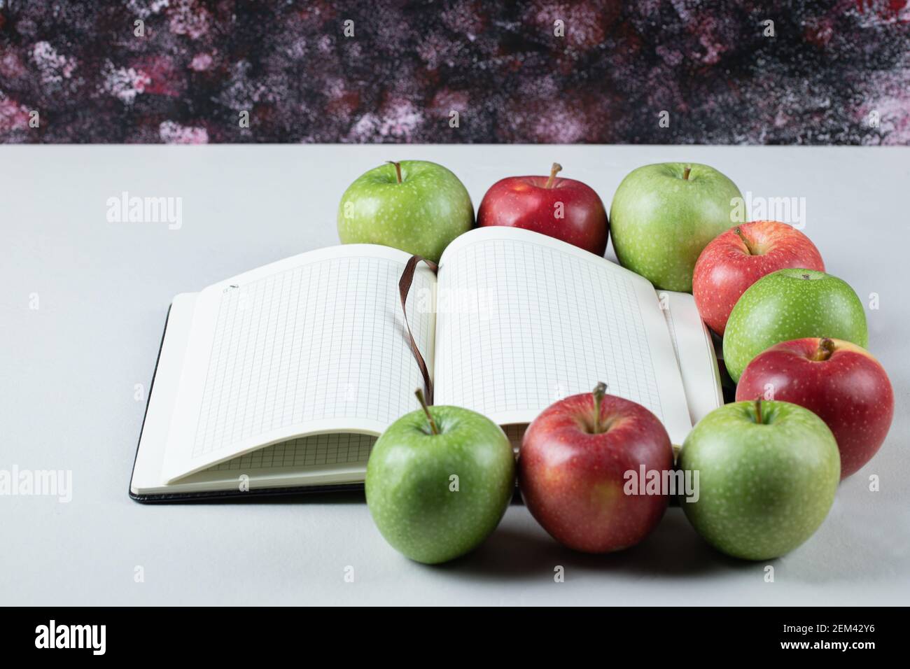 Rote und grüne Äpfel mit einem leeren Rezeptbuch zur Seite Stockfoto