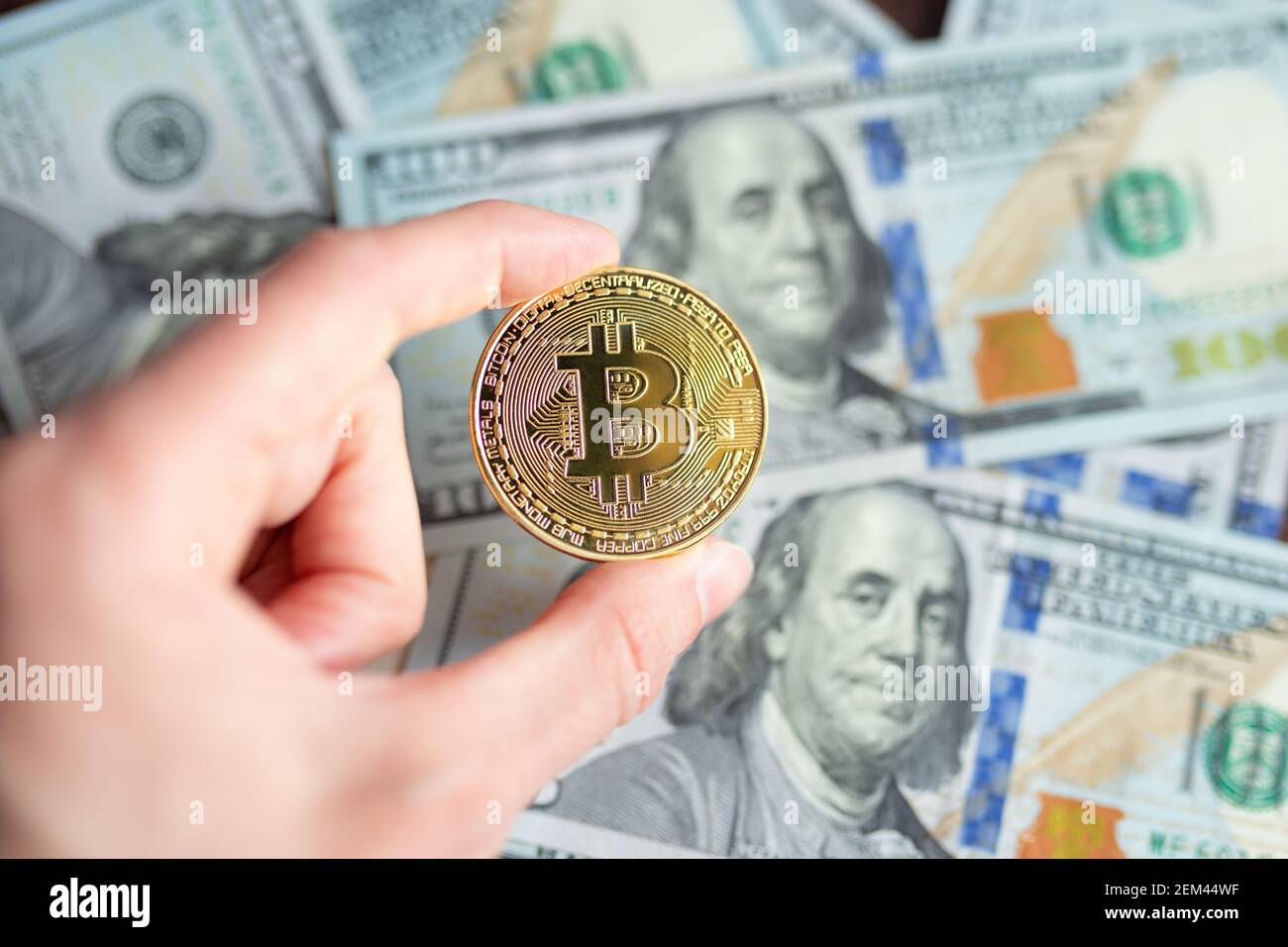 Hand hält Bitcoin über Währungen. Bitcoins und das neue Konzept des virtuellen Geldes. Bitcoin-Wachstum. Stockfoto