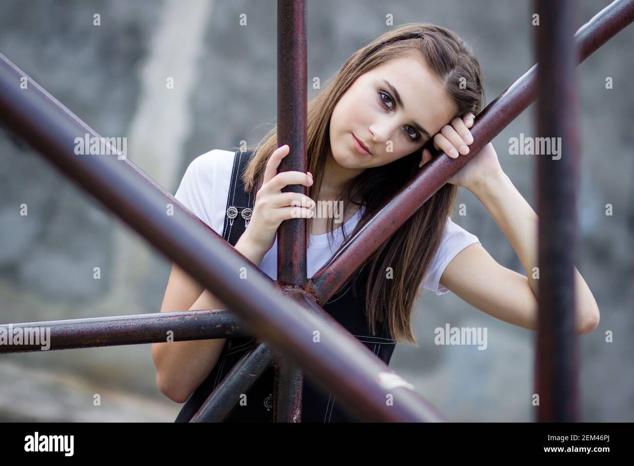 Porträt eines Brünette Mädchen im Freien, lehnte sich auf den Metallzaun Stockfoto
