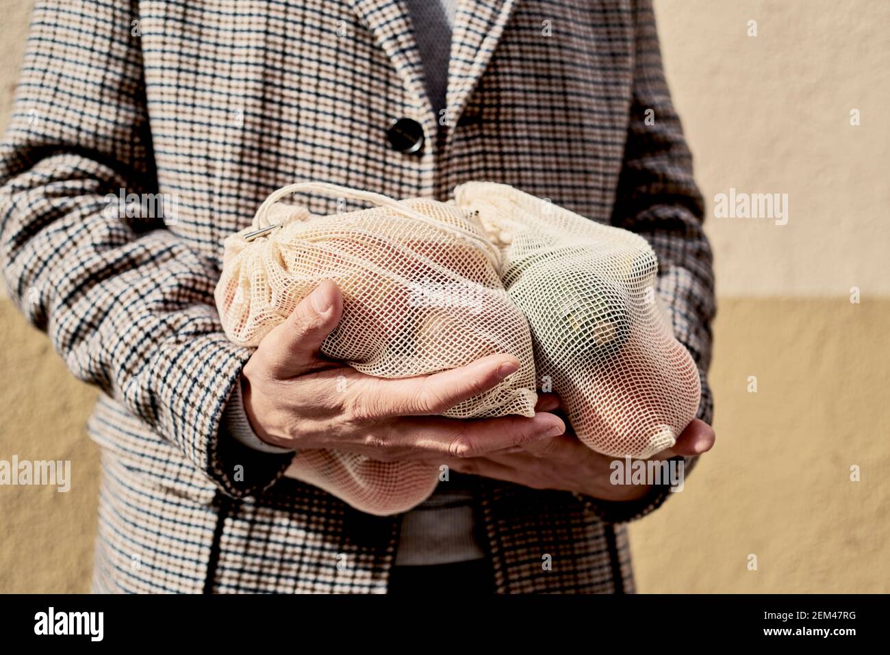 Ein junger Kaukasianer trägt auf der Straße einige wiederverwendbare Textilbeutel, die verwendet werden, um Lebensmittel in großen Mengen zu kaufen, voll mit Obst und Gemüse, als Messu Stockfoto