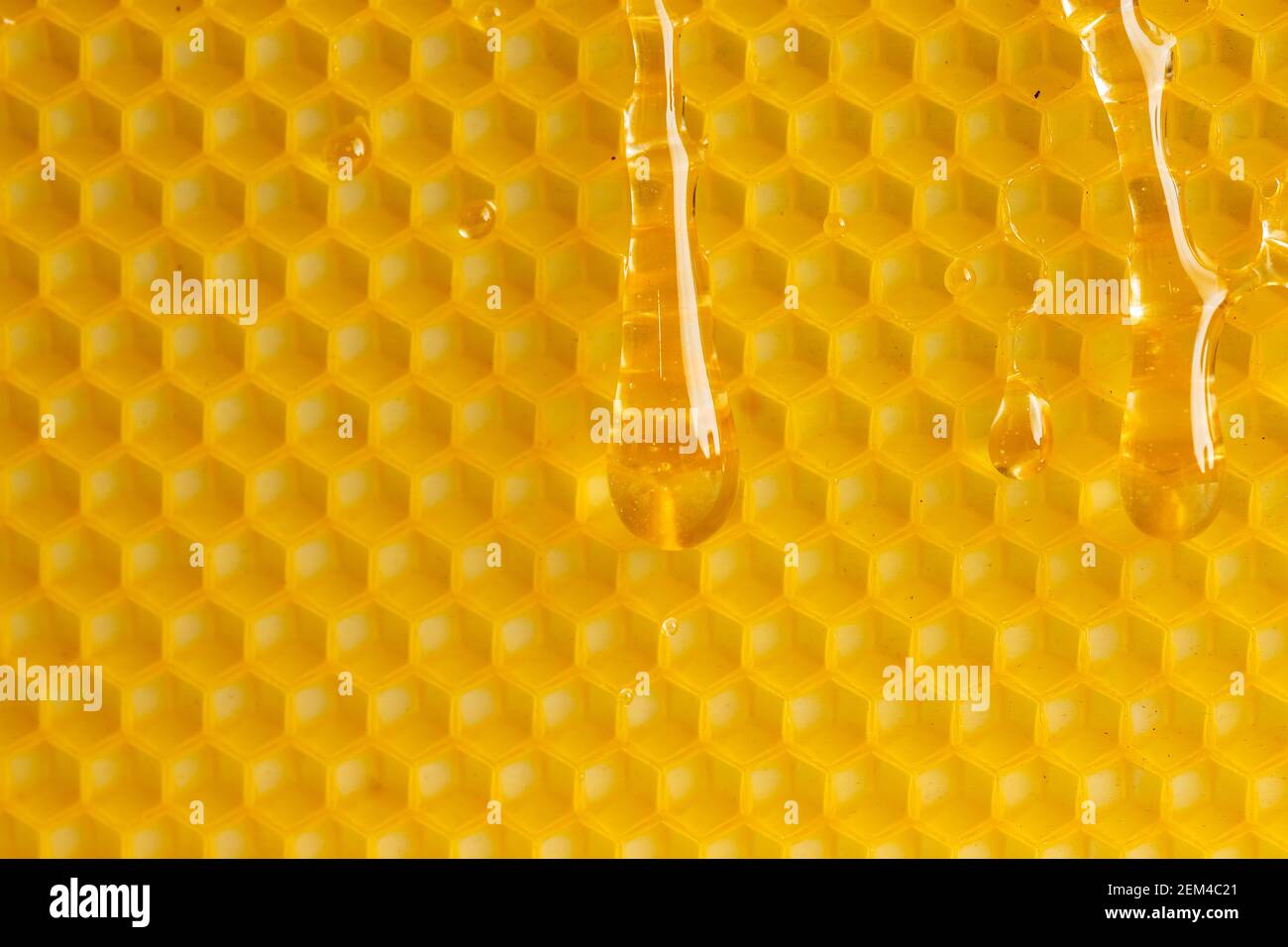 Makro Foto Tropfen Honig fließt nach unten auf gelbem Wachs, Textur Hintergrund. Stockfoto