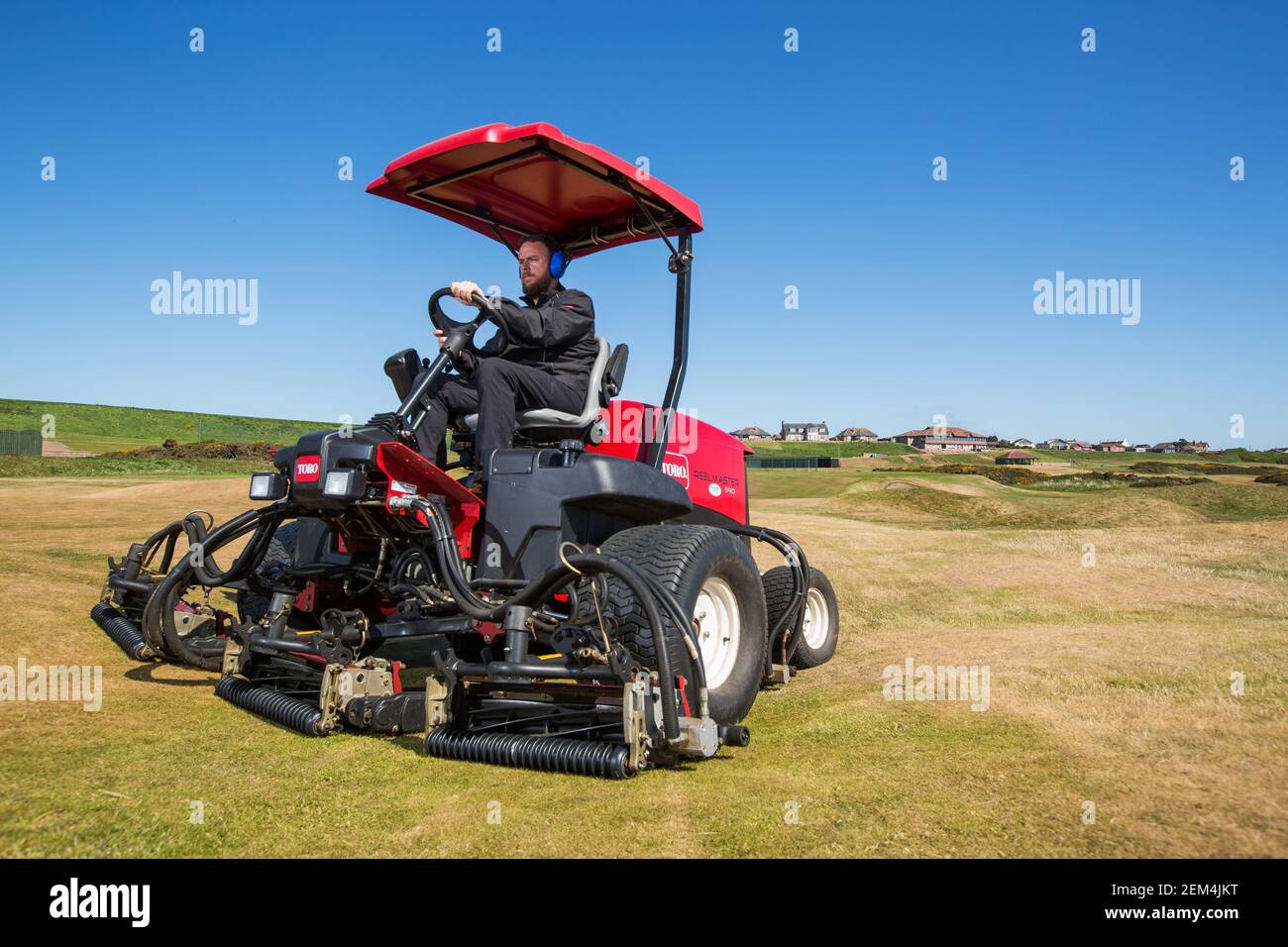 Ein Greenkeeper mit einer modernen Mähmaschine auf dem Golf Kurs Stockfoto