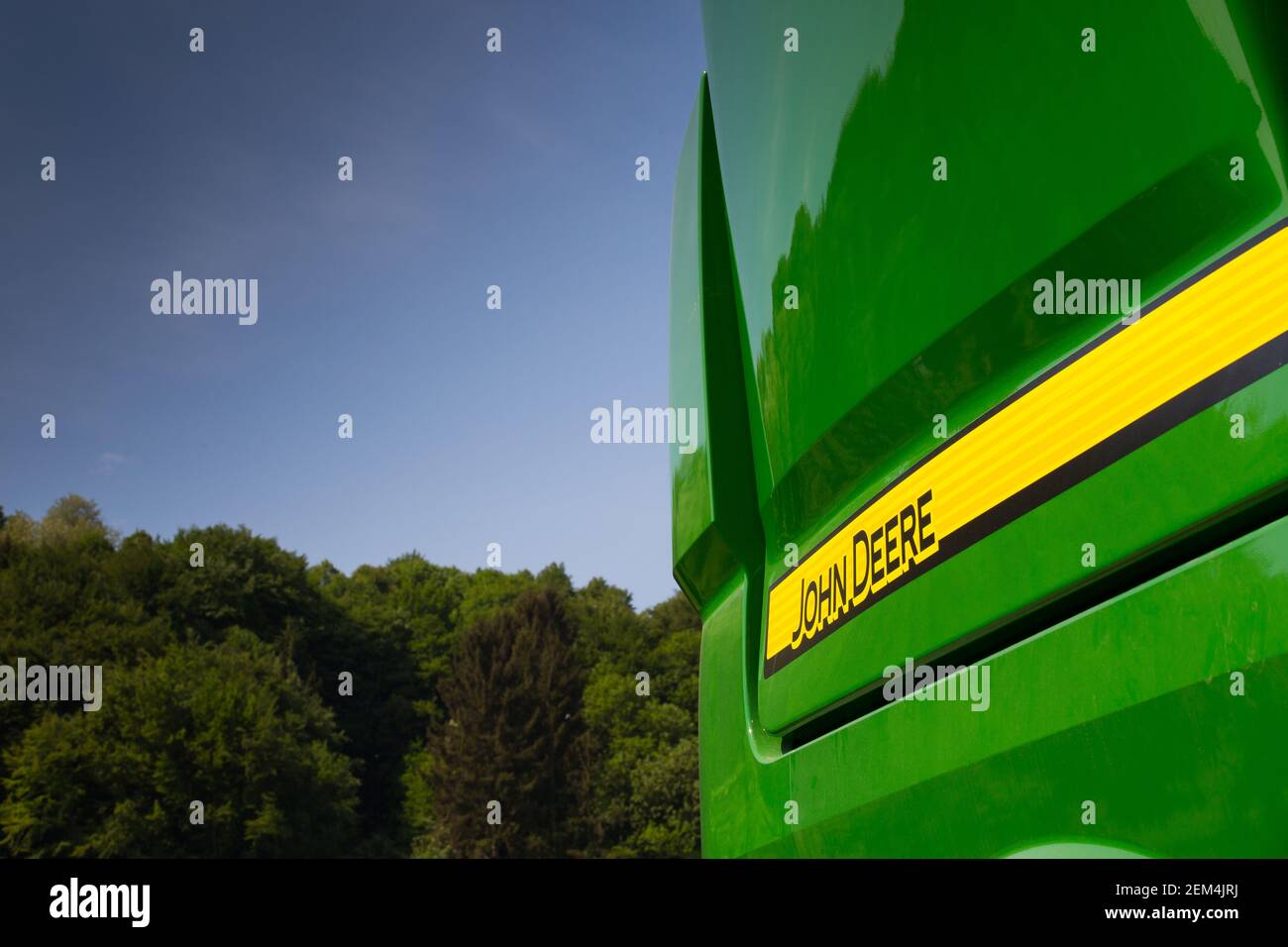 John Deere Zeichen auf landwirtschaftliche Maschine in Sonnenschein mit blau Himmel und Bäume Stockfoto