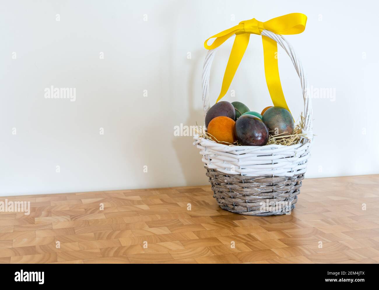 Stillleben von marmorierten farbigen Ostereiern im Weidenkorb Mit gelbem Band Stockfoto