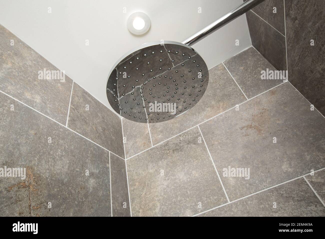 Ein großer, moderner Duschkopf in einer grau gefliesten Dusche Stockfoto
