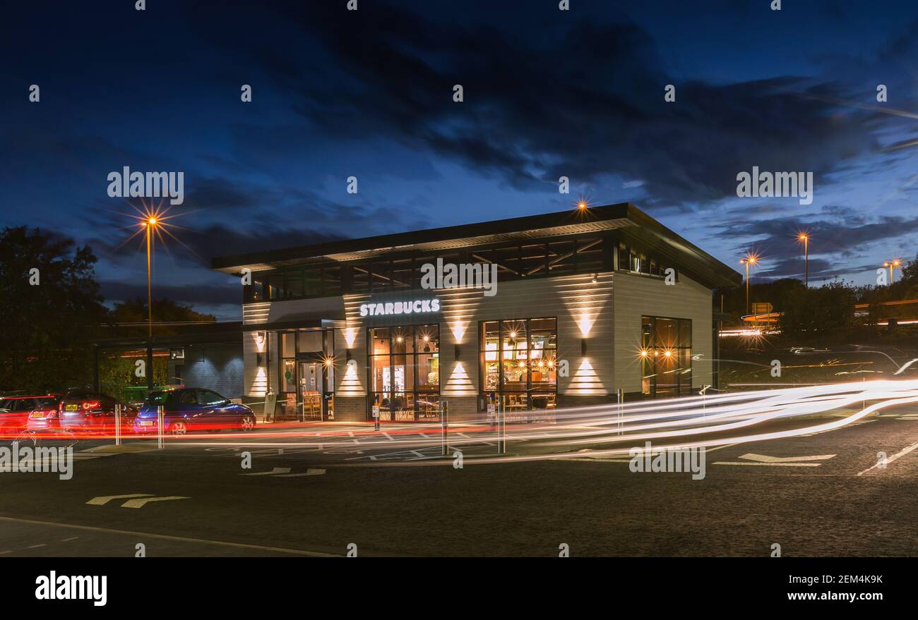 Ein geschäftiges Starbucks Kaffeestake Restaurant und nehmen Sie mit dem Verkehr weg Leichte Wanderwege bei Nacht Stockfoto