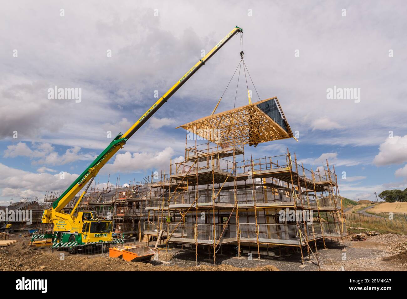 Ein Zeitschaltdach, das mit einem Kran auf einen teilweise abgesenkt wird Modernes Haus gebaut Stockfoto