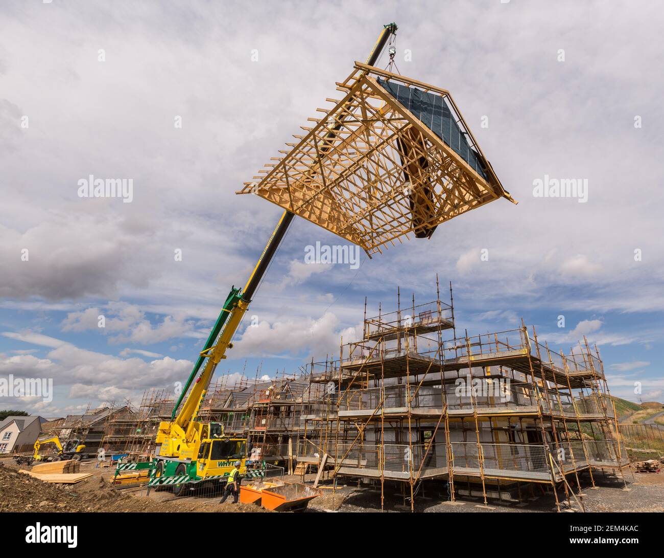 Ein Zeitschaltdach, das mit einem Kran auf einen teilweise abgesenkt wird Modernes Haus gebaut Stockfoto