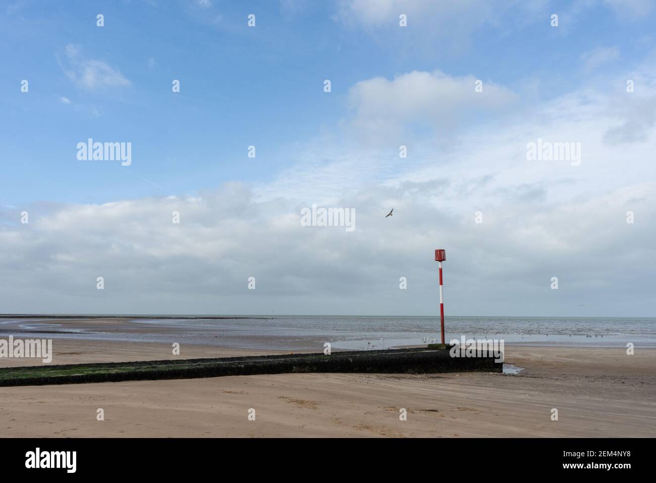 Die Bucht von Margate an schönen sonnigen Tag am Strand mit einer Möwe und Seebreaker und rot-weißen Pol-Leuchtfeuer, ist die Flut mit bewölktem Himmel Stockfoto