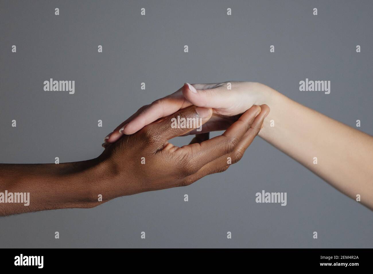 Die schwarze Hand hält die weiße Hand in ihrer Handfläche. Kampf gegen Rassismus Konzept. Stockfoto