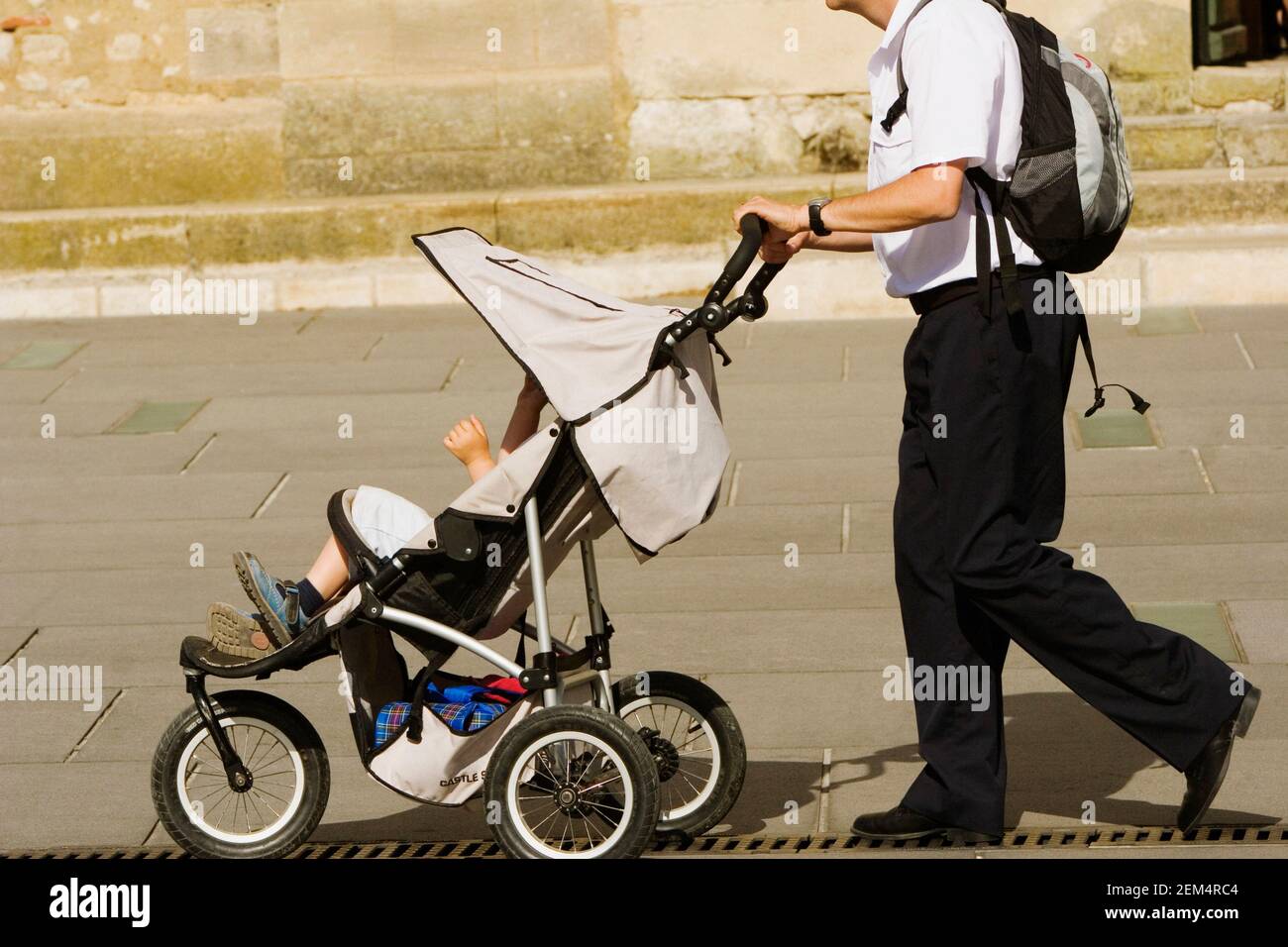 Seitenprofil eines Mannes, der seinen Sohn in einen schiebt Kinderwagen Stockfoto
