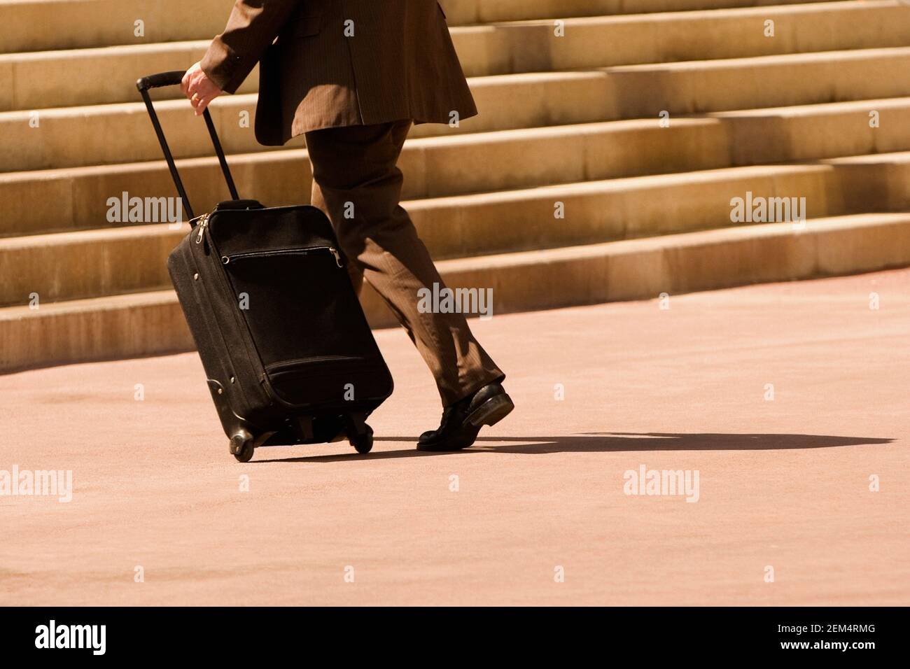 Seitenprofil eines Geschäftsmannes, der mit einem Koffer läuft Stockfoto