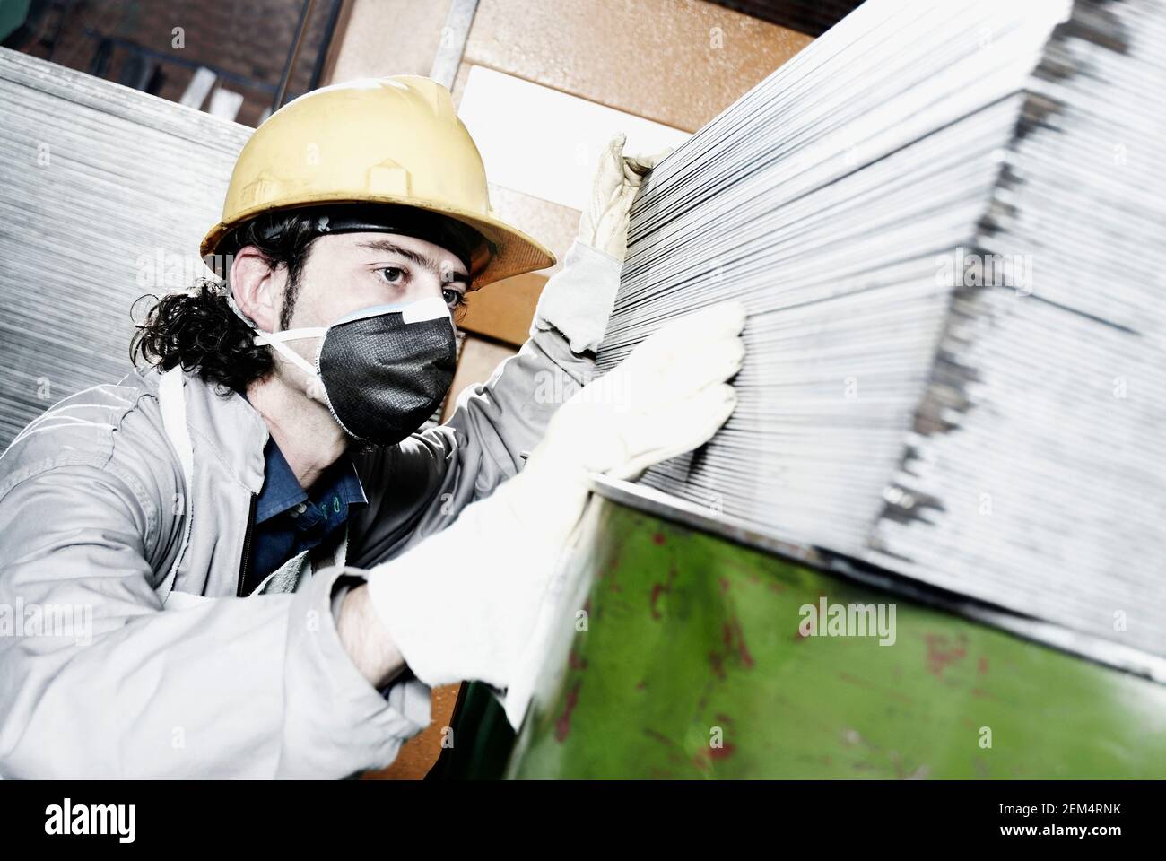 Nahaufnahme eines Mannes mit mittlerem Erwachsenenalter, der einen Hardhut und trägt Arbeiten in einer Fabrik Stockfoto