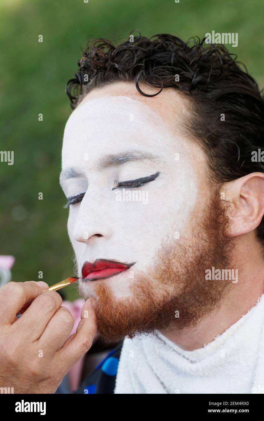 Nahaufnahme der Hand einer Person, die Make-up auf einem MID anwendet Gesicht eines erwachsenen Mannes Stockfoto