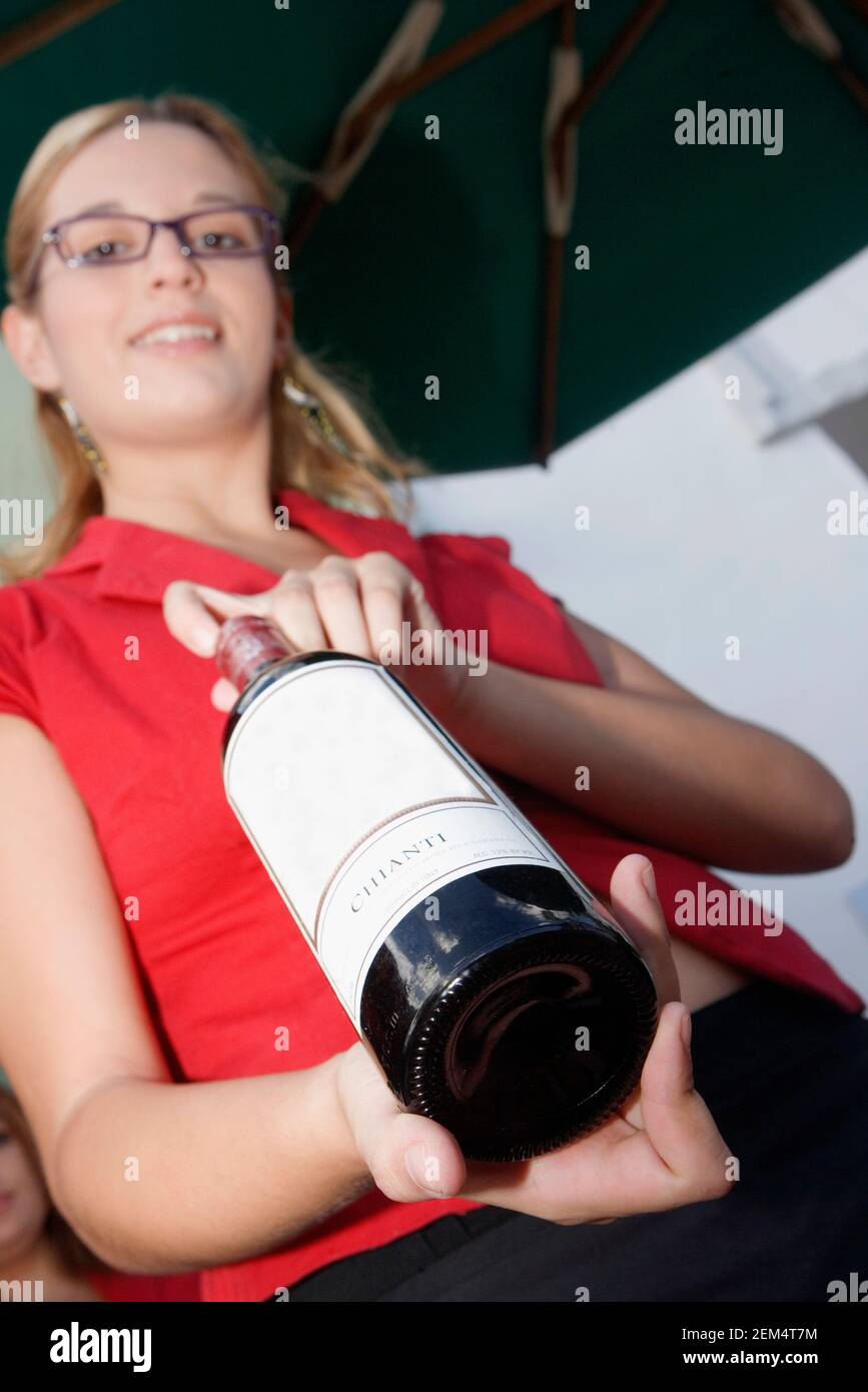 Porträt einer jungen Frau mit einer roten Flasche Wein Stockfoto