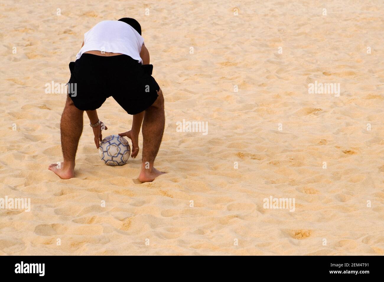 Rückansicht eines Mannes, der einen Strandball abholt Stockfoto