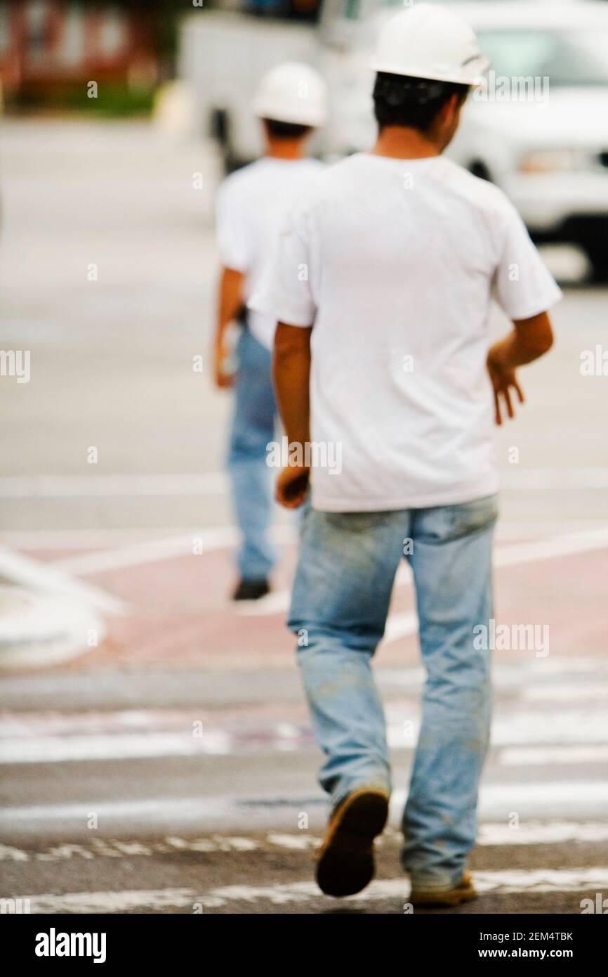 Rückansicht von zwei Arbeitern, die auf der Straße gehen Stockfoto