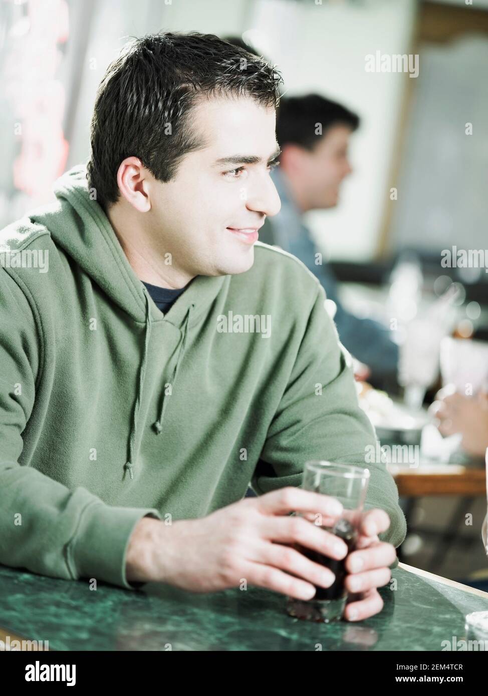 Nahaufnahme eines jungen Mannes, der ein Glas Wein in der Hand hält In einem Restaurant Stockfoto